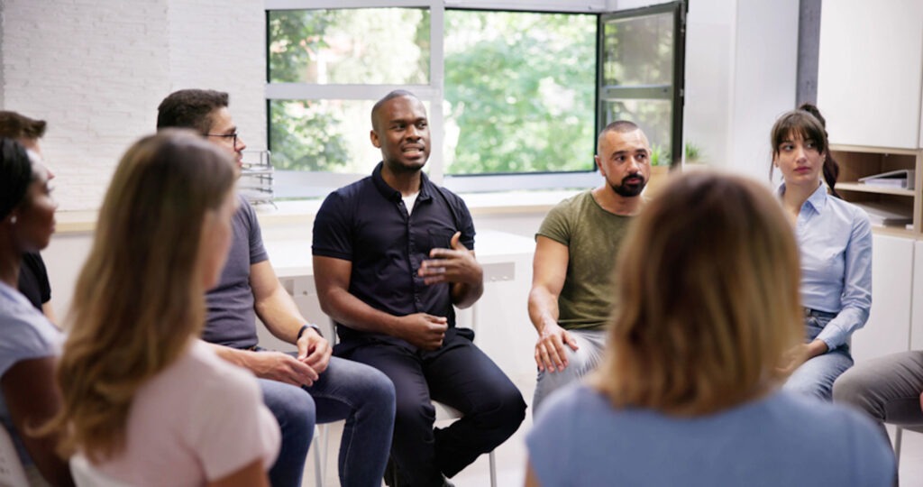 man speaking in group addiction therapy session