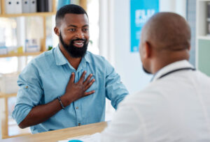 man with his hand on his chest communicating with medical professional