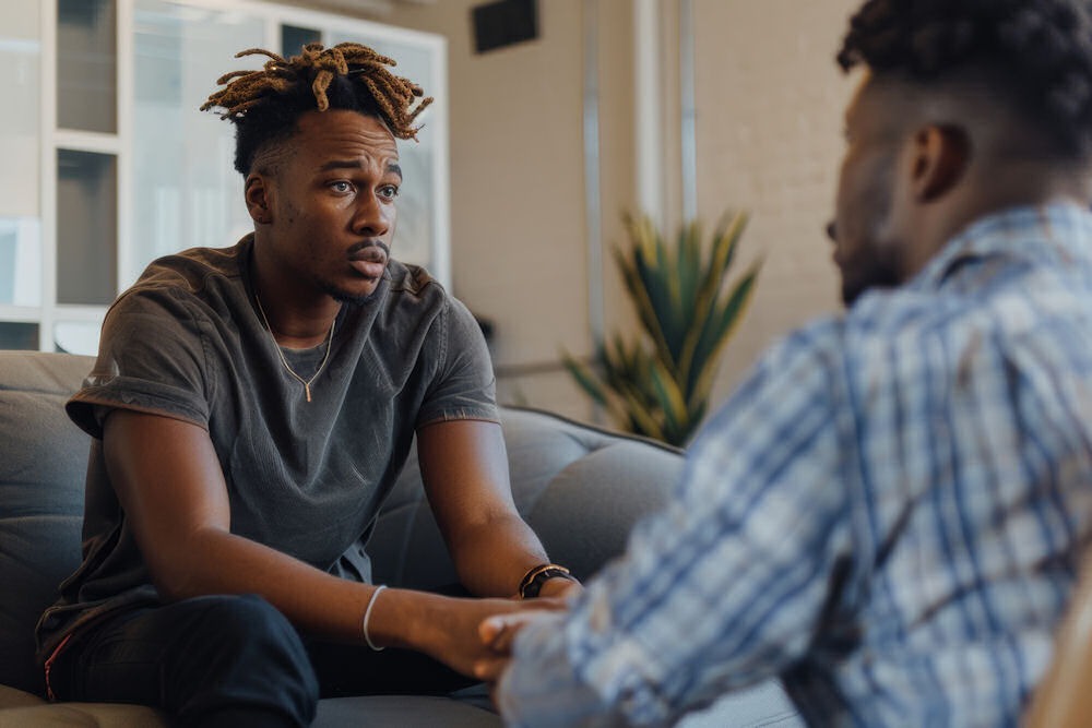 man sitting on couch having a talk with another man opposite of him