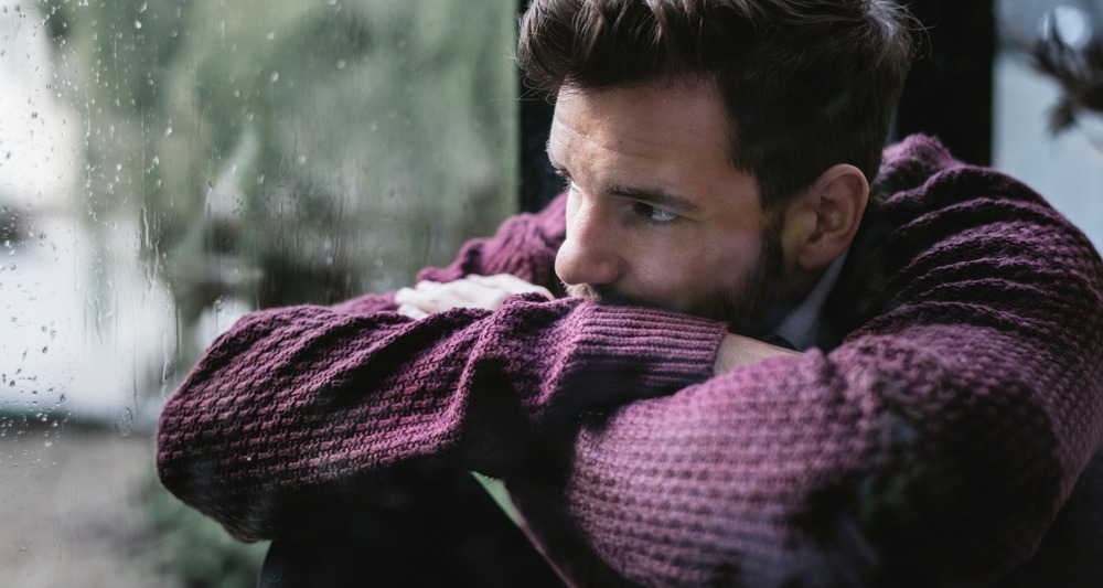 Man staring out a window, reflecting on the dangers of fentanyl use and its consequences