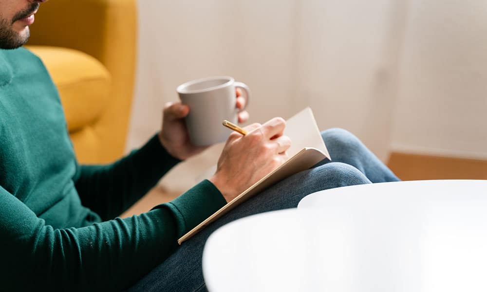 Person journaling and reflecting on behaviors, emotions, and patterns