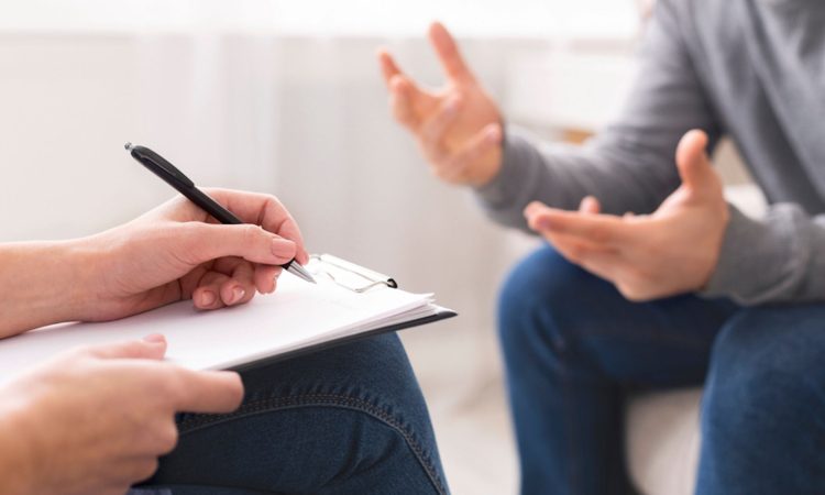Psychotherapist writing notes, giving diagnosis to emotional man patient at counseling session, free space