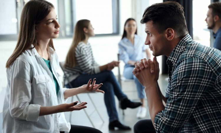man and woman sharing stories during group therapy meeting